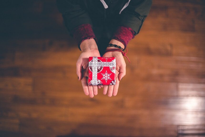 Image, small box wrapped in Christmas paper held out in two hands